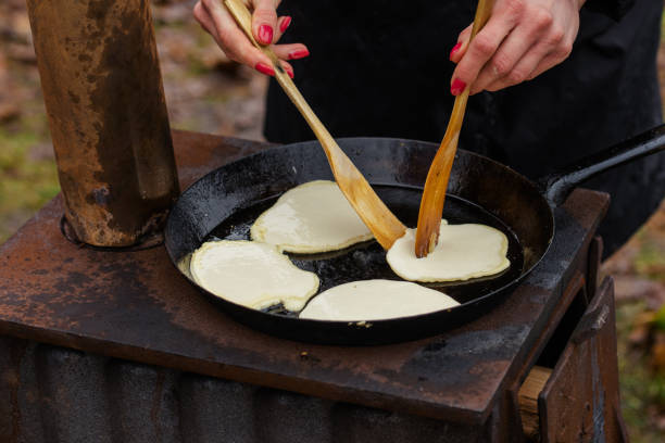 Preparing blini, blin or blynai, pancakes traditionally made from wheat or buckwheat flour and served with smetana, tvorog, butter, caviar and other garnishes, preparing outdoor on an open fire