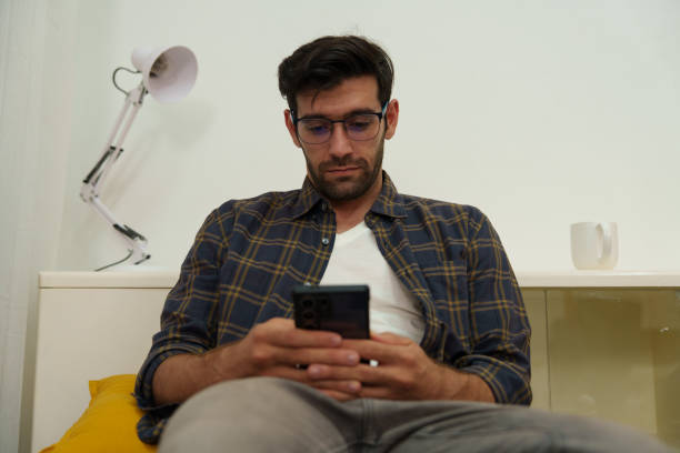 istock A man is playing with his mobile phone in the living room. 2203189677