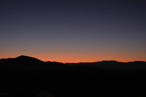 A breathtaking twilight sky over a mountain range, with a gradient of deep blue and warm orange hues, creating a peaceful and serene landscape view.