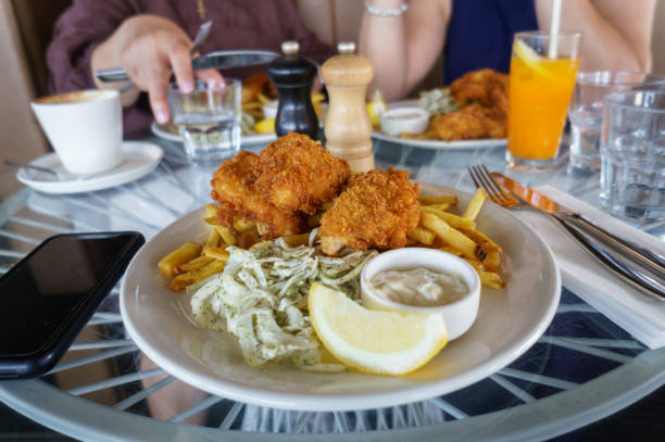 Fish and chips on a plate in a restaurant. Unrecognizable people in the background. Auckland.