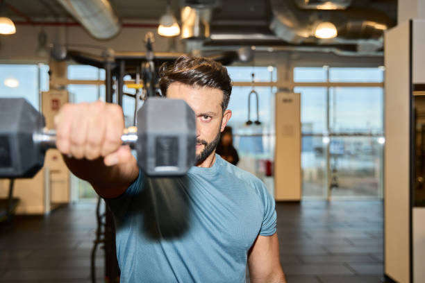 istock Focused man lifting dumbbell in modern gym 2203190753