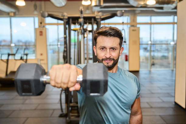 istock Focused man lifting dumbbell in modern gym 2203190839