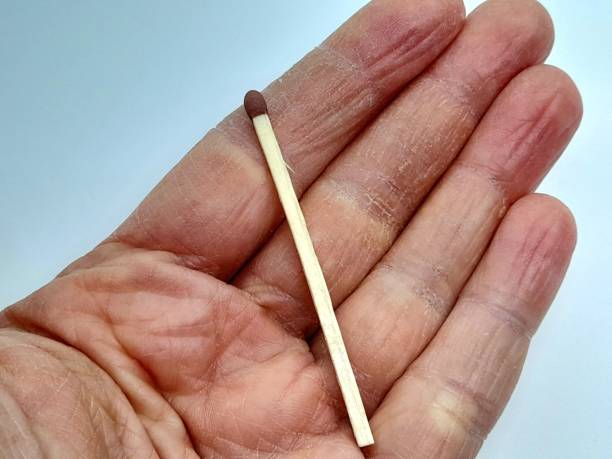 istock One match in hand with white background. 2203191030