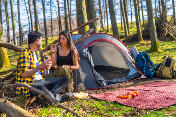 istock Hikers enjoying snacks in front of tent during camping trip in forest 2203191324