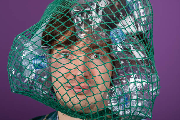 istock A powerful image capturing a person's face obscured by a net filled with plastic bottles, symbolizing the impact of waste on the environment. 2203195466