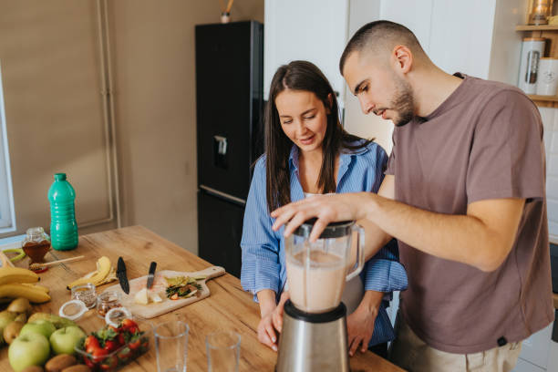 istock Happy couple preparing healthy fruit smoothie at home 2203195776
