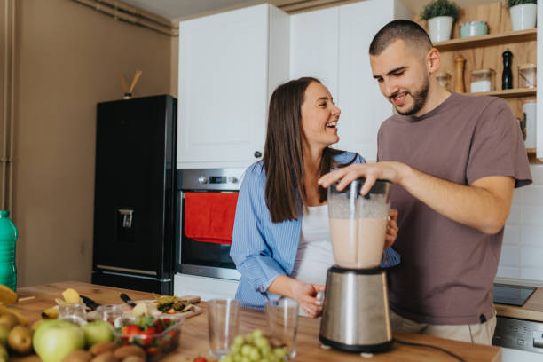 istock Happy couple preparing healthy fruit smoothie at home 2203196250