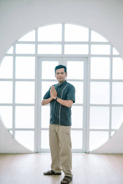 istock Respectful asian man greeting with hands clasped in front bright window 2203197091
