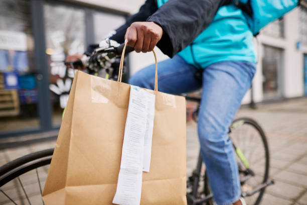 Courier carrying a grocery bag while riding a bicycle