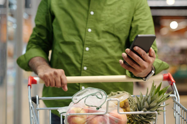 istock Man Using Smartphone in Supermarket 2203198693