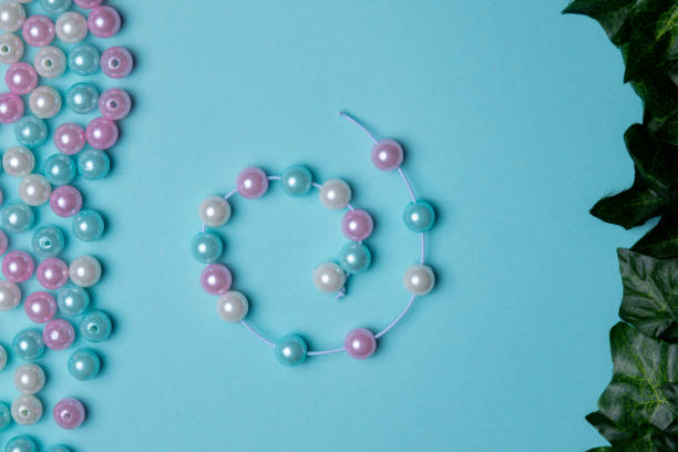 Different colored beads are spread across a blue background, with a completed bracelet made from matching beads laid out nearby.