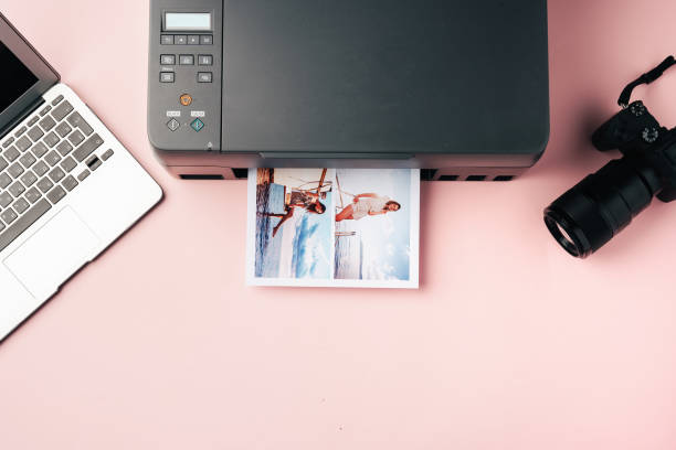 istock Printer, laptop and camera on table close up. Printing photos 2203200397
