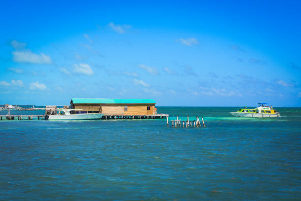 Caye Caulker offers breathtaking views of the turquoise waters, wooden buildings, and boats on a sunny day, creating an inviting atmosphere.