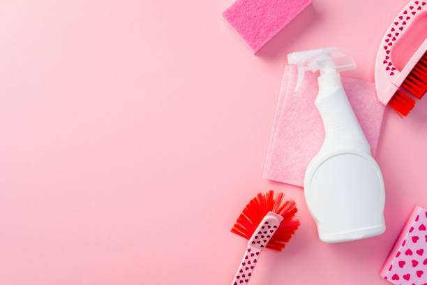 istock Cleaning supplies with heart patterns and white detergent spray bottle on a pink background. 2203202474