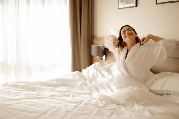 istock Morning Bliss: Woman Waking Up and Stretching in a Bed 2203203874
