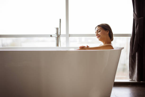 Happy woman taking bath with foam in tub indoors