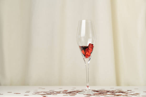 Wine glass with heart confetti on cream background. Minimalist holiday photo for Valentines