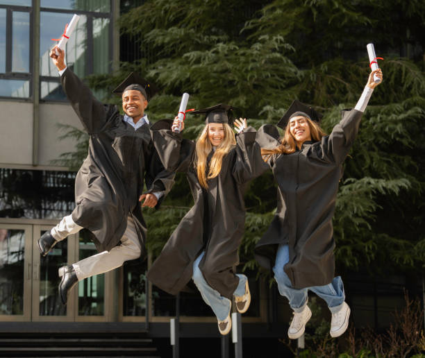 istock Three cheerful multiethnic graduating students jumping for joy, holding their diplomas, celebrating their academic achievement 2203205075