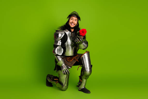istock A smiling knight in armor holding a rose posing against a bright green studio backdrop 2203206028