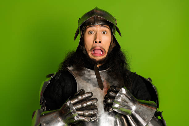 istock Funny young knight in medieval armor expressing surprise on a bright green background 2203206108