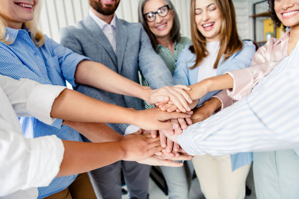istock Group of professionals joining hands in a collaborative office setting celebrating teamwork 2203206872