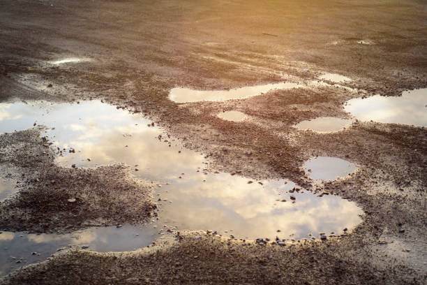 istock Water ponds in asphalt ground at sunset 2203207758