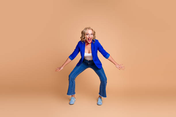 istock Woman in blue blazer posing on beige background with excited expression demonstrating her cheerful spirit 2203211160