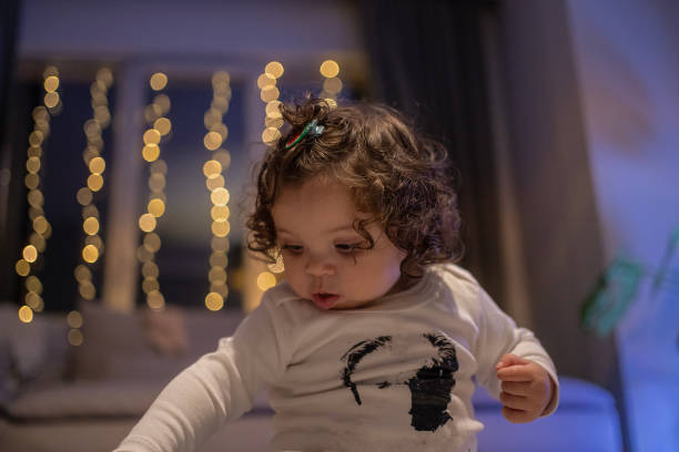 istock Curious Baby with Twinkling Lights in the Background 2203211290