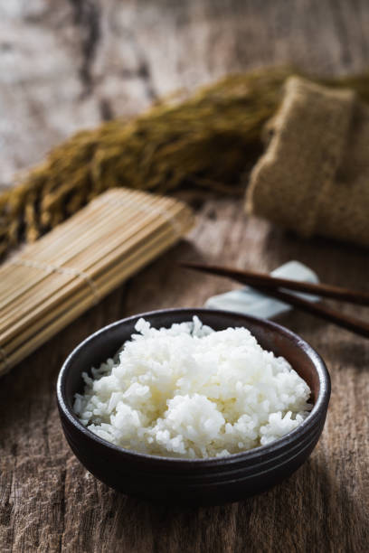 istock Bowl of Steamed White Rice on Rustic Wooden Table with Utensils and Background Elements 2203211993