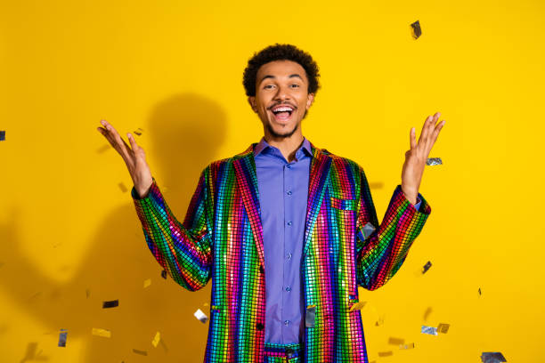 istock Charismatic young man in a stylish, vibrant multicolored jacket celebrates cheerfully against a lively yellow background. 2203212748