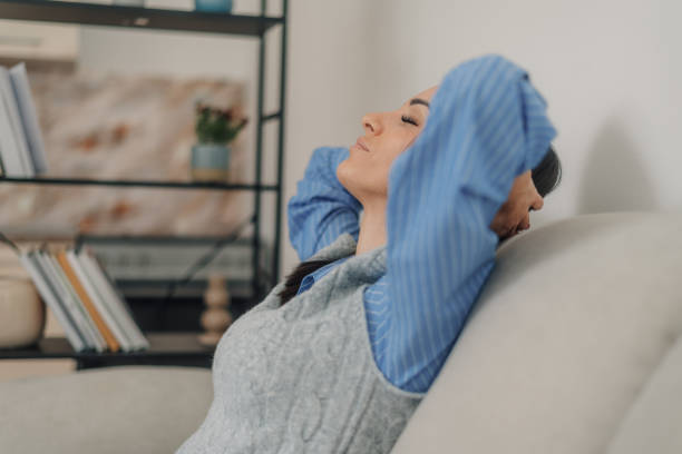 istock Woman relaxing on sofa with hands behind head at home 2203213637