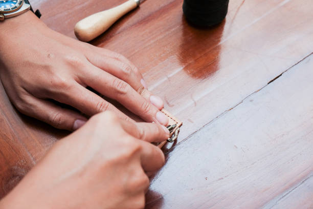 istock Close up of a hand man or artisan worker hands. Leather craft tools on old wood table 2203214762