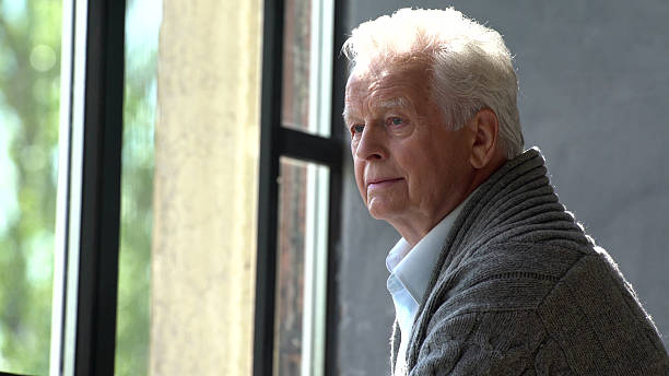 istock Elderly caucasian man look at window lost in thought 2203217843