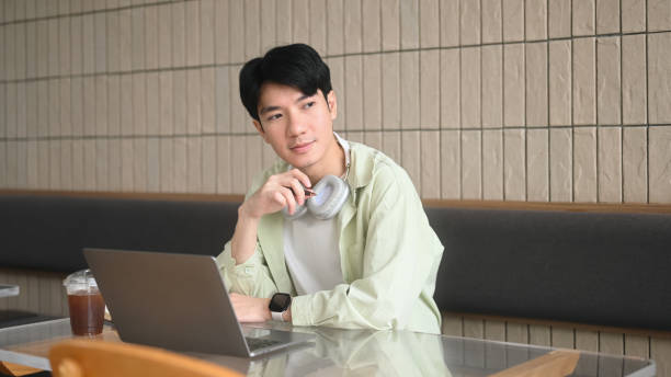 istock A young man in a casual setting reflects while working on his laptop, illustrating the thoughtfulness of modern e-learning environments 2203219682