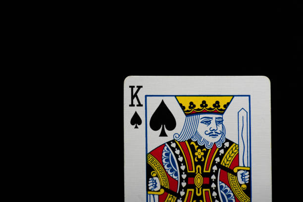 A hand picking up, giving or secretly showing three playing cards, ace, queen and king of heart over red poker table against black background for Royal Flush, in Poker, Gambling, casino related backdrops with copy space.