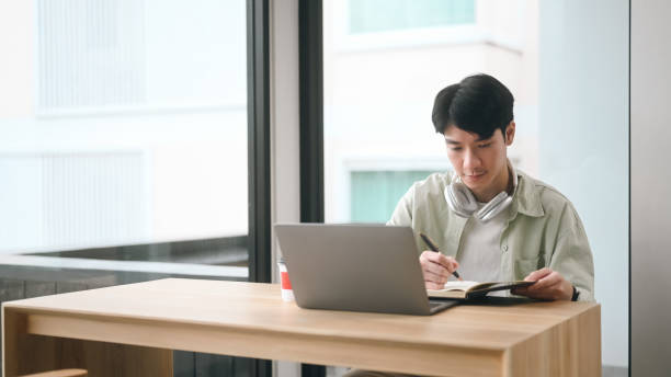 istock A man is sitting at a table with a laptop and a notebook 2203221220