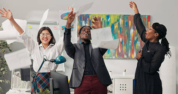istock Assistant in office shouts after reading a winning bid, while co-workers cheer, laugh, and throw documents in the air. 2203222858