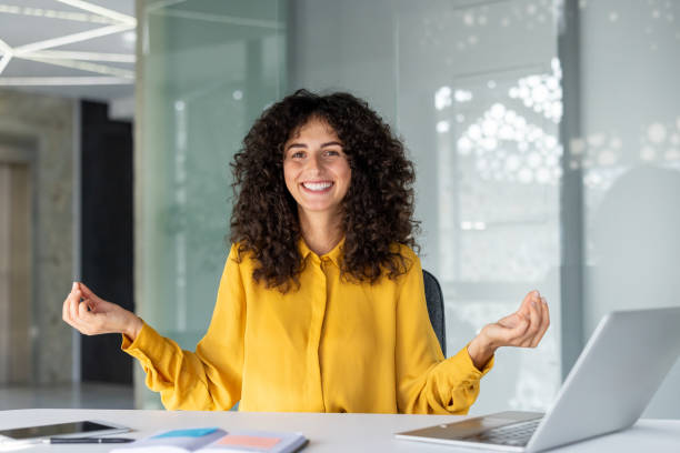 istock Woman meditating at desk in modern office setting during work break 2203223149