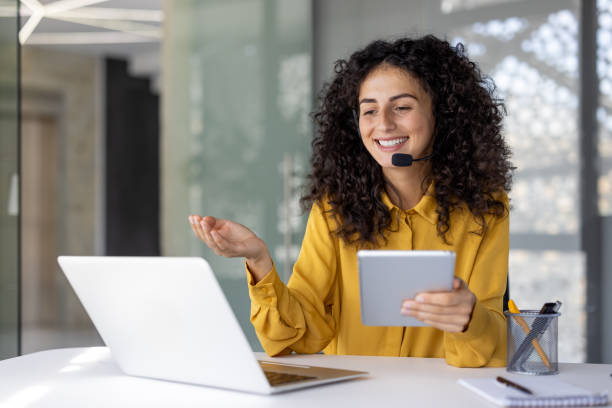 istock Support service worker, businesswoman with headset and tablet in hands communicates and consults clients remotely, office worker smiles satisfied uses laptop inside office 2203223196