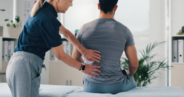 istock Back massage, physical therapy and patient at consultation for problem, inflammation or muscle strain. People, chiropractor and treatment for injury, rehabilitation and recovery of spinal ligaments 2203223832