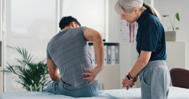 istock Back pain, physical therapy and patient at consultation for problem, inflammation or muscle strain. People, chiropractor and treatment for injury, rehabilitation and recovery of spinal ligaments 2203223833