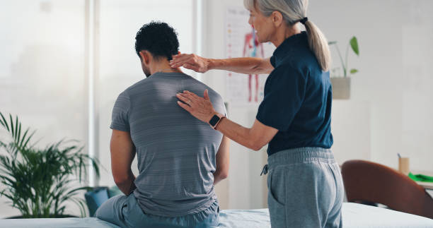 Physiotherapy, back massage and patient man at consultation for spinal problem or inflammation. Person, chiropractor and touch for injury, rehabilitation and recovery of muscle damage clinic bed