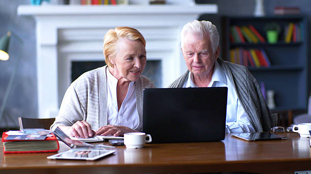 istock Senior couple looks at laptop with interest and makes note in notebook. 2203223969