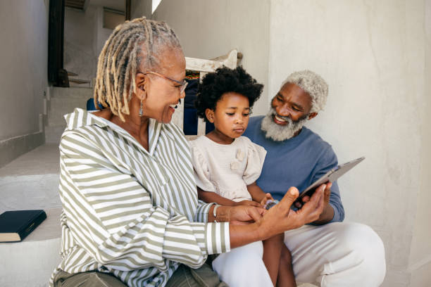 istock A happy multigenerational family sits together on a bright porch, sharing laughter while exploring something on a tablet. 2203225316