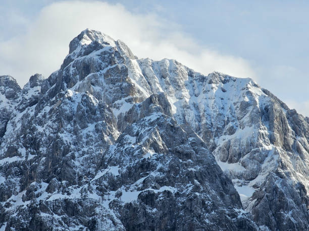 Majestic snow-capped mountain peaks rise towards a bright blue sky, creating a breathtaking winter landscape in triglav national park, slovenia