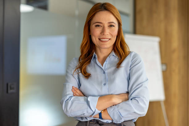 istock Confident businesswoman smiling with folded arms in office 2203228747