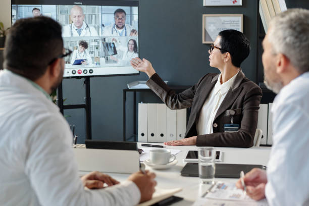 istock Female Medical Pointing at Virtual Conference Screen 2203229421