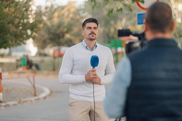 istock Journalist reporting live news with microphone and cameraman 2203230868