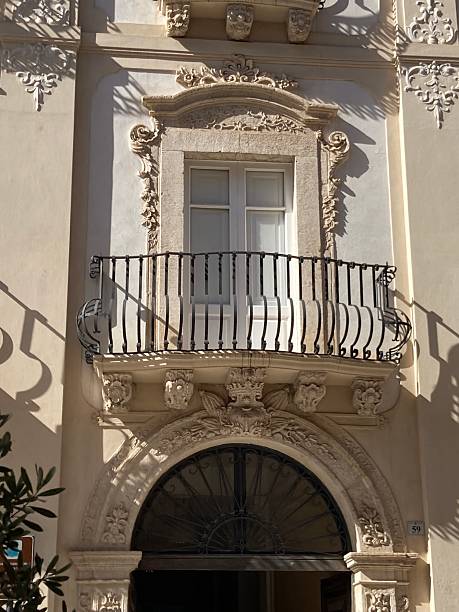 istock Baroque decorated window facade with wrought iron balcony over decorated lunette window with relief pillars. 2203234976