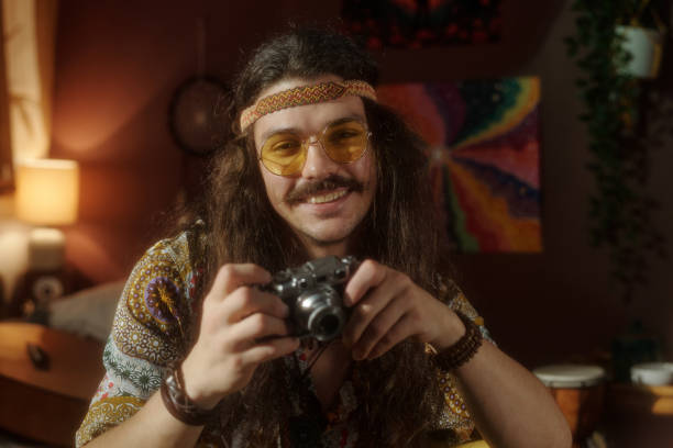 istock Smiling Man Holding Camera Sitting in Cozy Room 2203238069